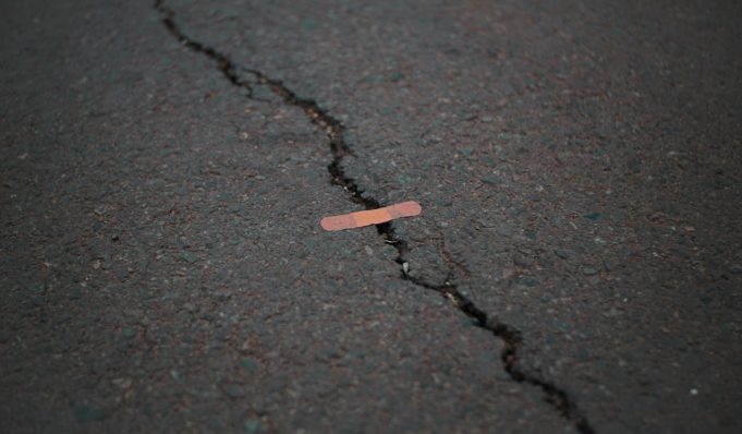 Cracked facade of a Melbourne office building after the 4.0 quake, with pedestrians inspecting damage on a city street.