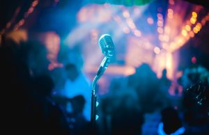 Toby Keith Dies at 62, Country Star Toby Keith performing on stage with a guitar, wearing a cowboy hat and smiling at the audience.