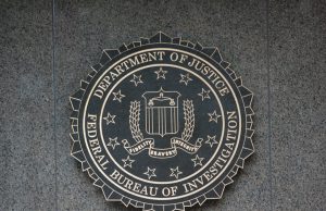FBI Releases Unidentified UAP Image to Pentagon Archive A grainy black-and-white image shows a small dark circular object in a crosshair reticle against a mountain range, labeled as FBI evidence submitted to the Pentagon.