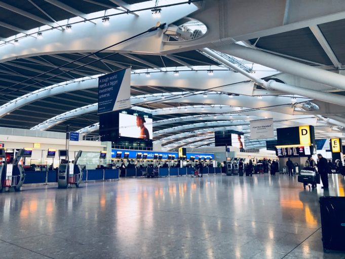 Crowded terminal at Indira Gandhi International Airport with a collapsed roof section and debris scattered on the floor.