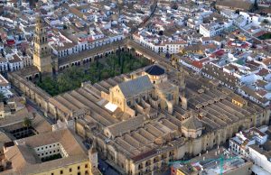 Córdoba Mosque-Cathedral Fire Collapses Chapel Roof Orange flames and smoke billow from the chapel roof of the striped-arch Mosque-Cathedral while firefighters spray water hoses at night.