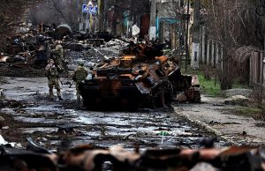 Ukraine Retakes Kyiv Suburbs, Finds Booby-Trapped Bodies Ukrainian soldiers advance past a damaged tank while using cables to drag a civilian body feared to be booby-trapped near Kyiv.