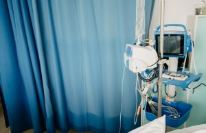 WHO Ends COVID-19 Emergency, Long COVID Persists A healthcare worker checks on a patient in a hospital bed, representing ongoing long COVID care after the emergency phase ends.