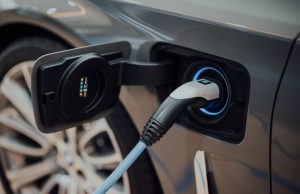 Wuling Hongguang Mini EV Hits 1.1 Million Sales A small Wuling Hongguang Mini EV parked on a busy Chinese city street, surrounded by pedestrians and larger vehicles.
