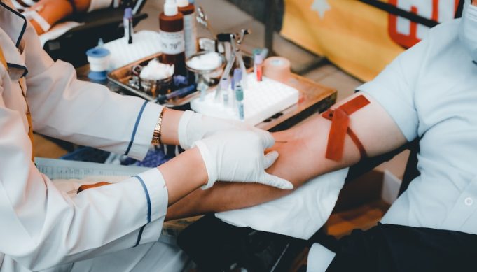 FDA Approves Lentiviral Gene Therapy Lyfgenia for Sickle Cell Disease A scientist examines a vial of Lyfgenia gene therapy in a laboratory, with DNA helix graphics in the background.