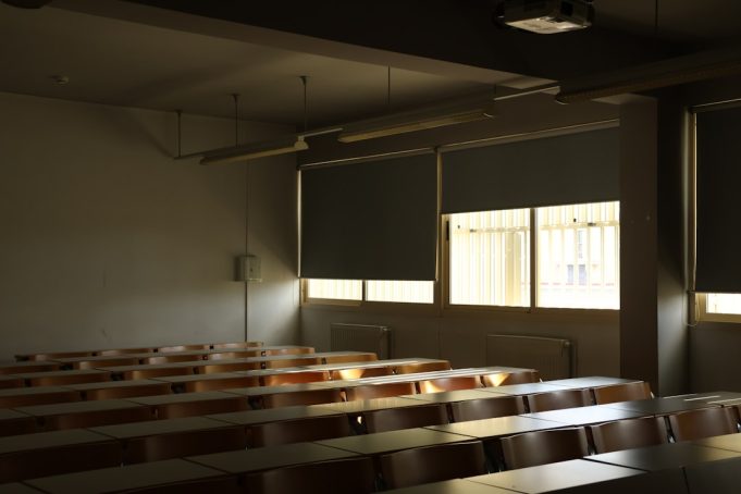 ChatGPT’s Arrival in Late 2022 Alters Classroom Grading and Teaching Teacher reviewing student essays while a phone displays ChatGPT on the desk in a dimly lit classroom.